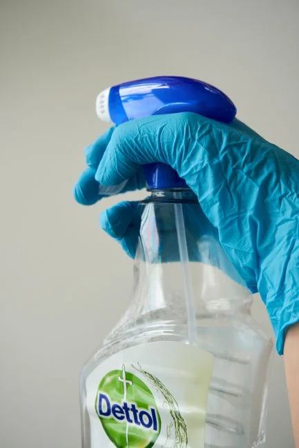 Woman holding eco-friendly cleaning products with blue microfiber cloth indoors.